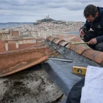 Rénovation toiture Marseille après mistral : couvreur inspecte une toiture abîmée